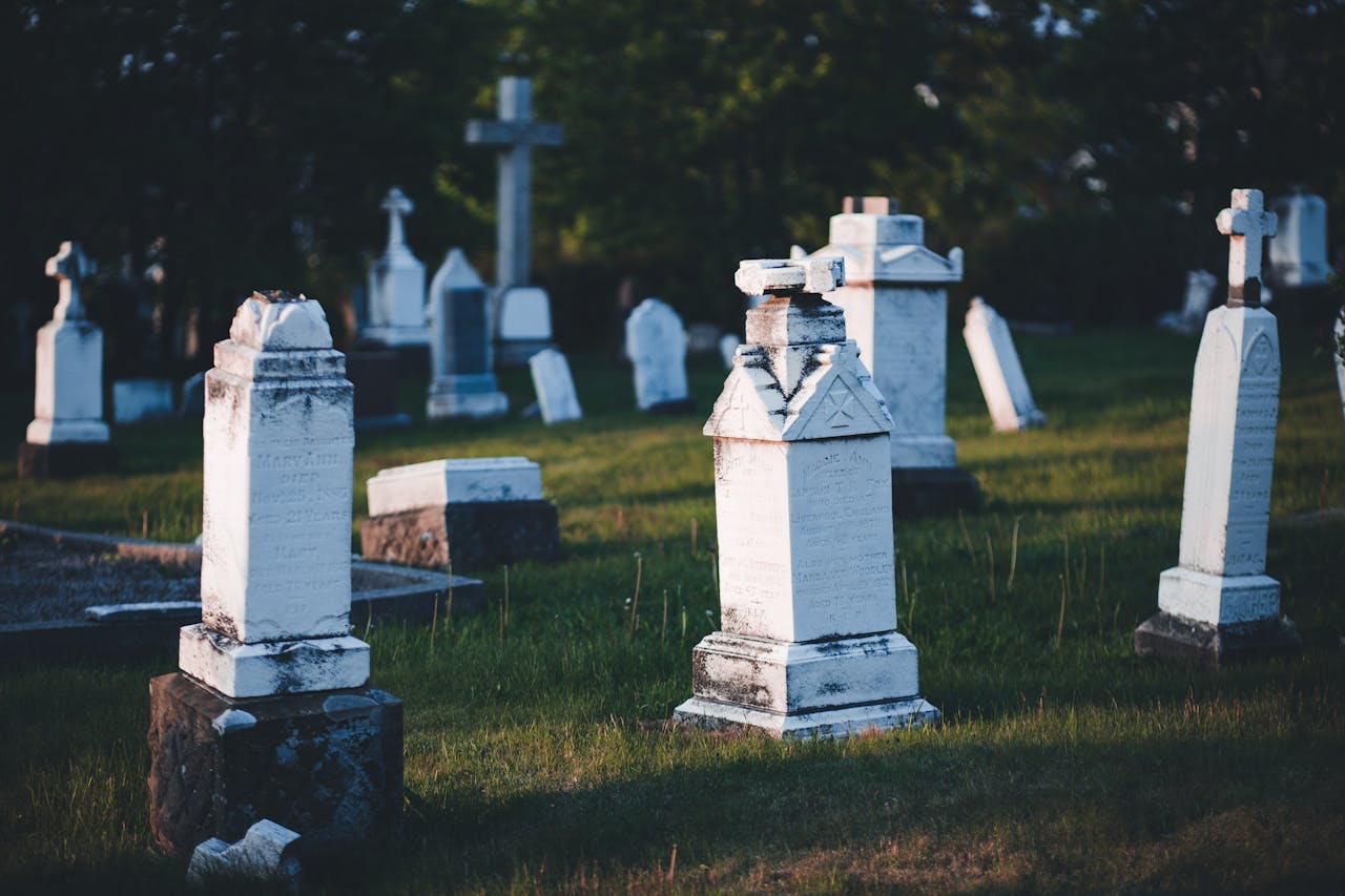 A peaceful cemetery scene with aged tombstones and crosses, captured at sunset with lush greenery.